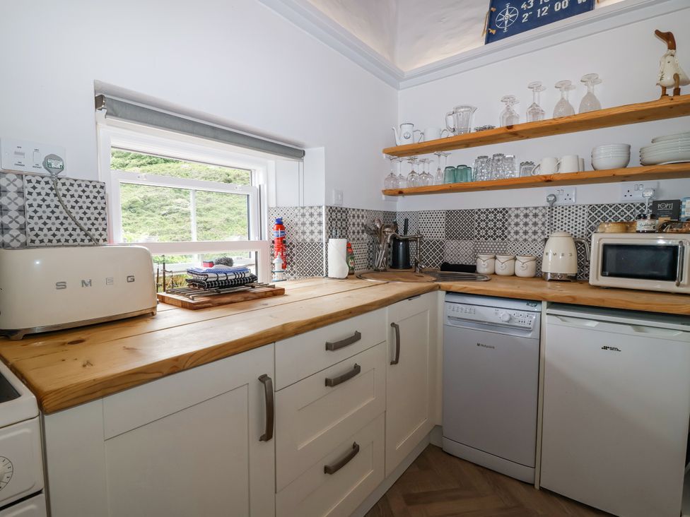 A kitchen with appliances and dishes on the counter at 2 Cliff Cottages West Portholland near Gorran Haven