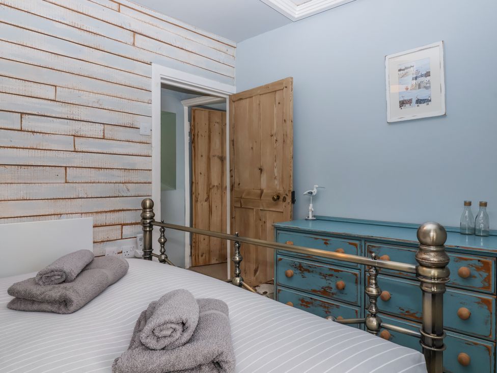 A bedroom with a bed and towels folded at 2 Cliff Cottages near West Portholland