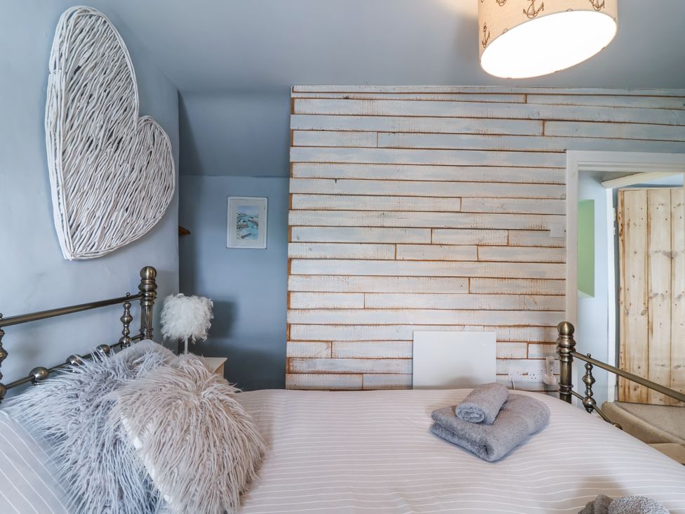 A bedroom with a bed and wall art at 2 Cliff Cottages West Portholland near Gorran Haven