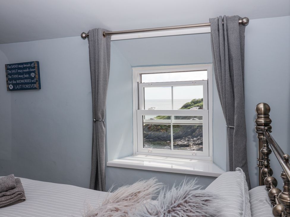 A bedroom with a window view at 2 Cliff Cottages in West Portholland near Gorran Haven