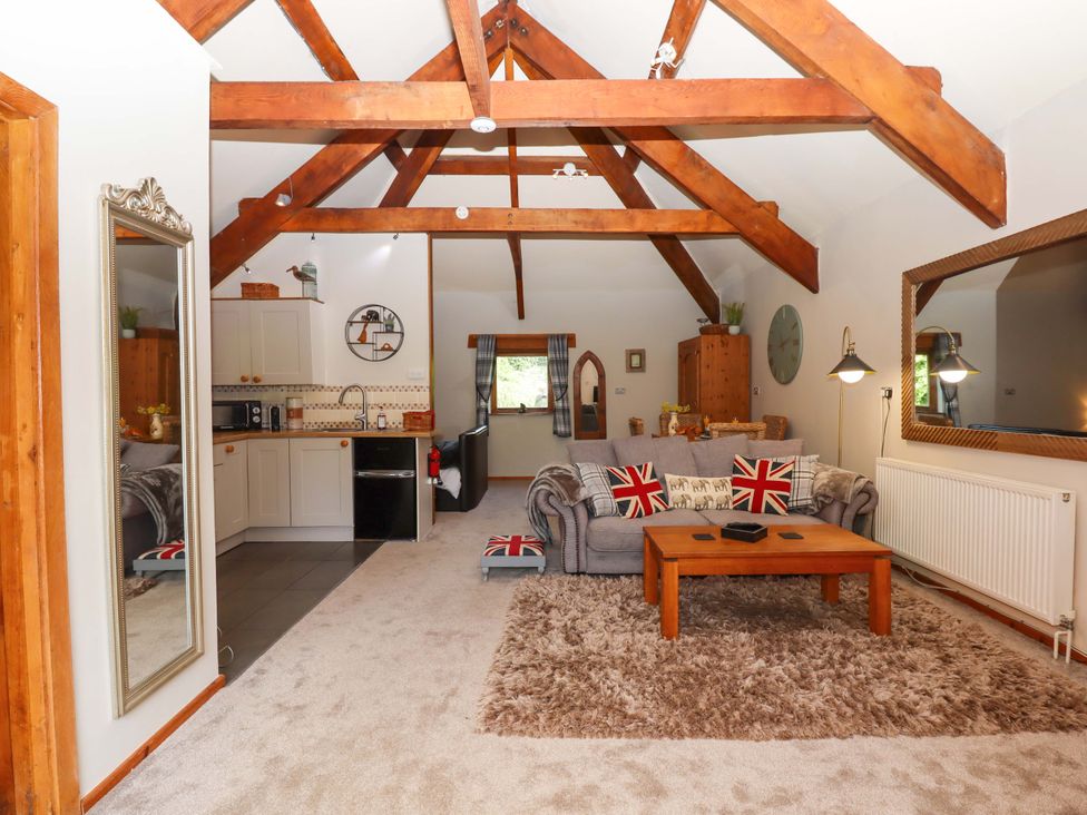 A living room with a sofa and kitchen area at Little Torr in Drewsteignton