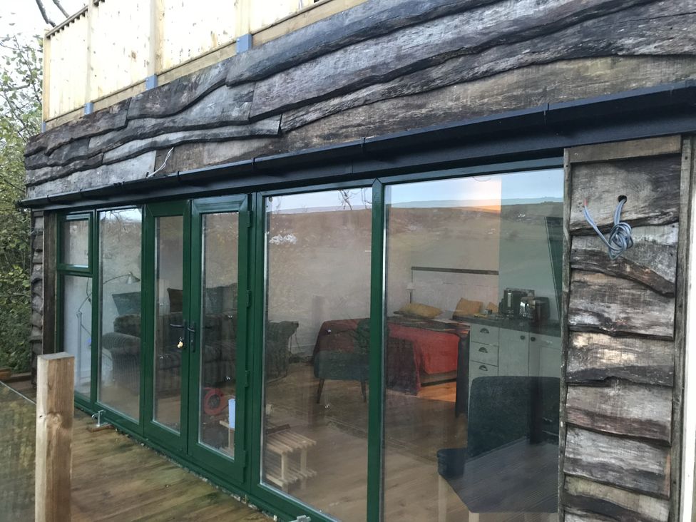 An outdoor view of a wooden structure with large glass doors at The Sett on the Wharfe Skipton