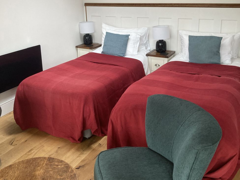 A bedroom with two beds and a chair at The Sett on the Wharfe Skipton