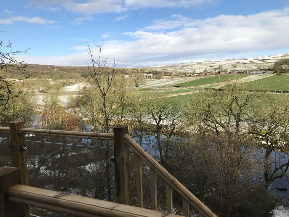 A view of a river and fields from a wooden railing at The Sett on the Wharfe Skipton