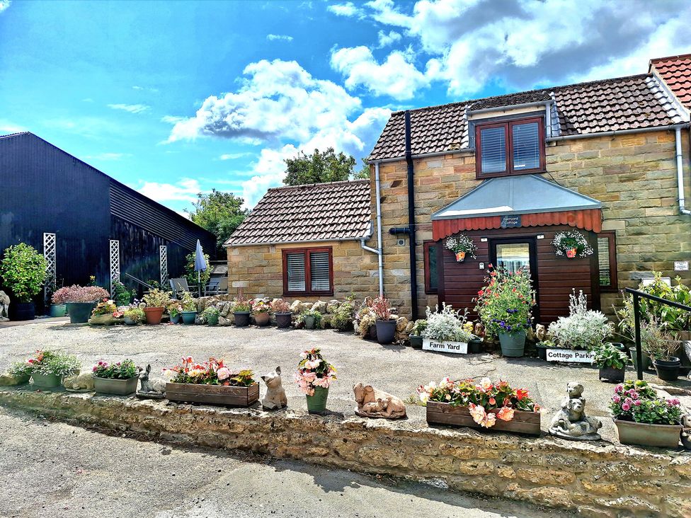 An outdoor area with a house and planters at Farm Yard Cottage in Allerston