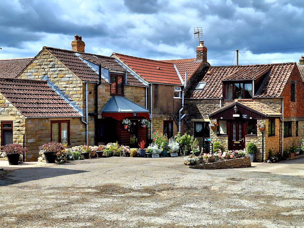 A stone house with flower pots in the courtyard at Farm Yard Cottage in Allerston