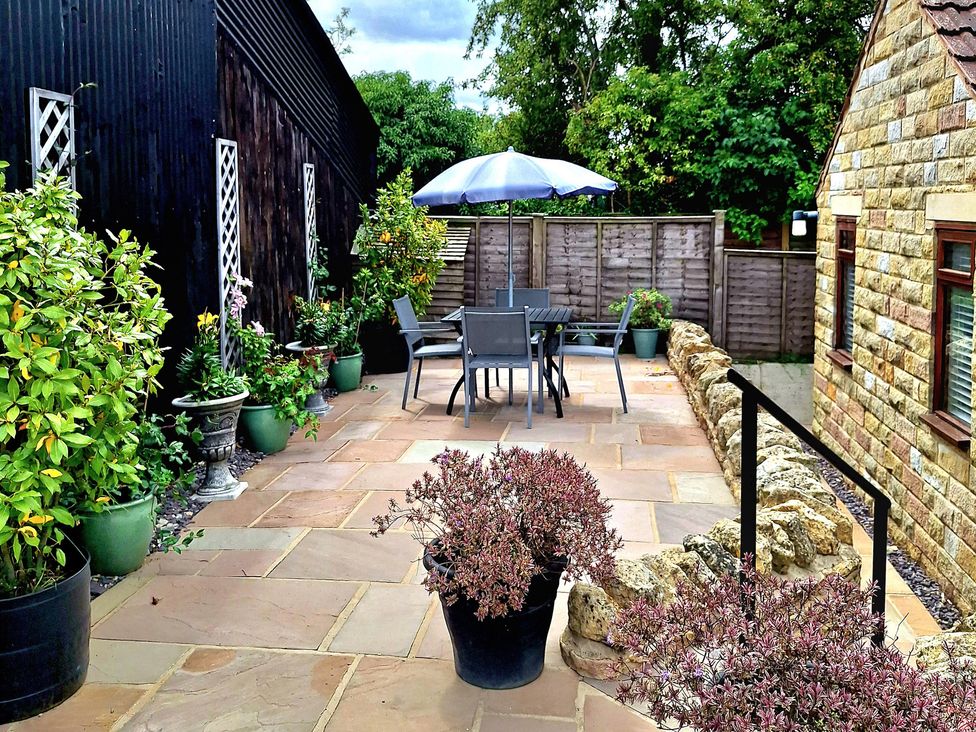 A garden with a seating area and potted plants at Farm Yard Cottage in Allerston