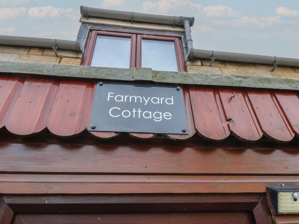 An outdoor view of a sign for Farmyard Cottage in Allerston