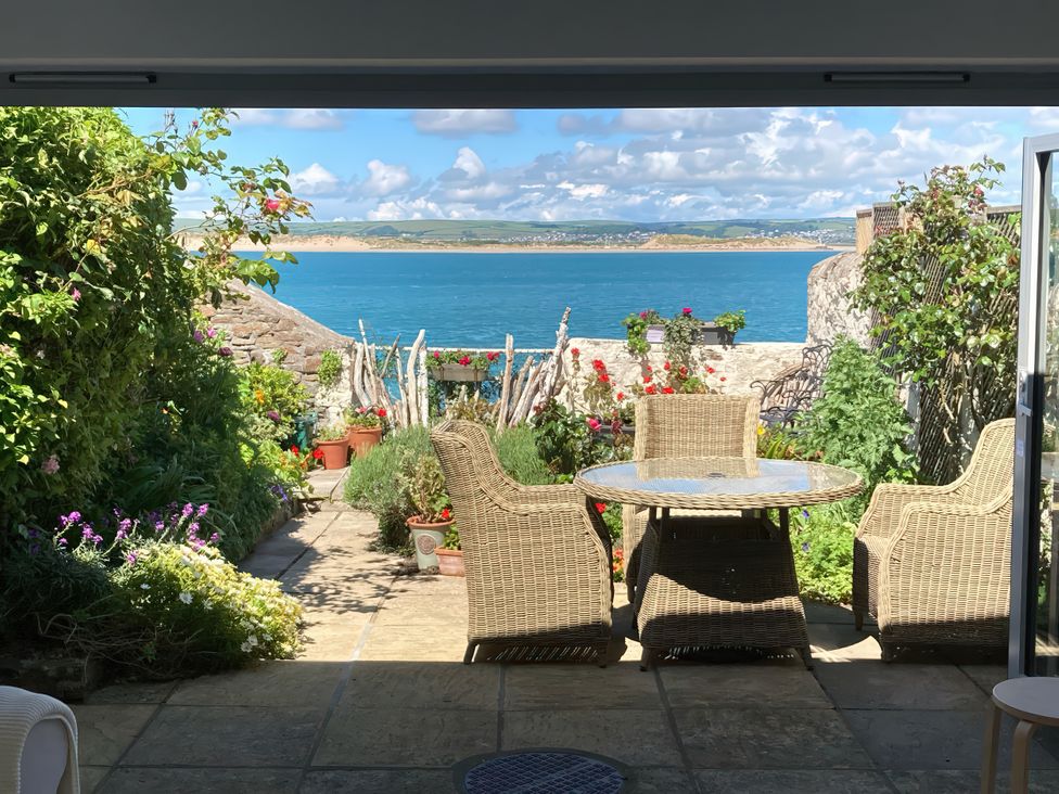 A garden with a table and chairs overlooking the sea at Mariners Cottage in Appledore
