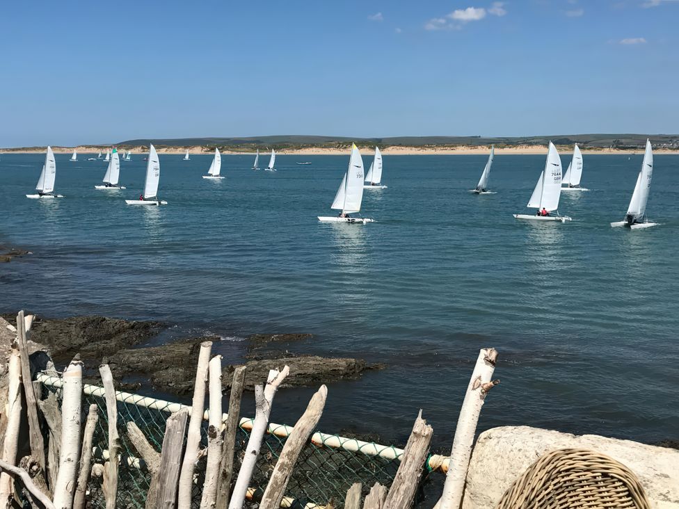 A view of sailboats on water near rocks and a fence at Mariners Cottage in Appledore