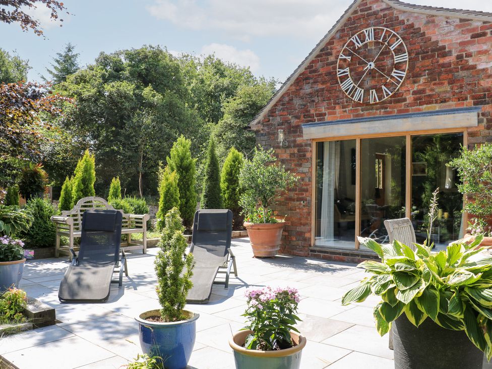 A garden with lounge chairs and potted plants at Ladycroft Barn in Ashbourne