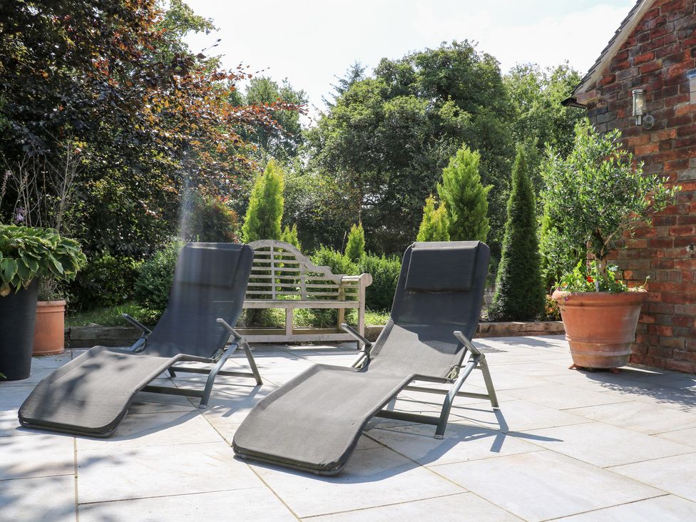 Two deck chairs and a garden bench in a garden at Ladycroft Barn Ashbourne