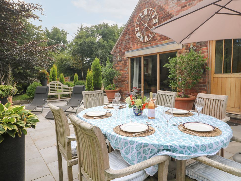 An outdoor dining setup with a table and chairs at Ladycroft Barn in Ashbourne