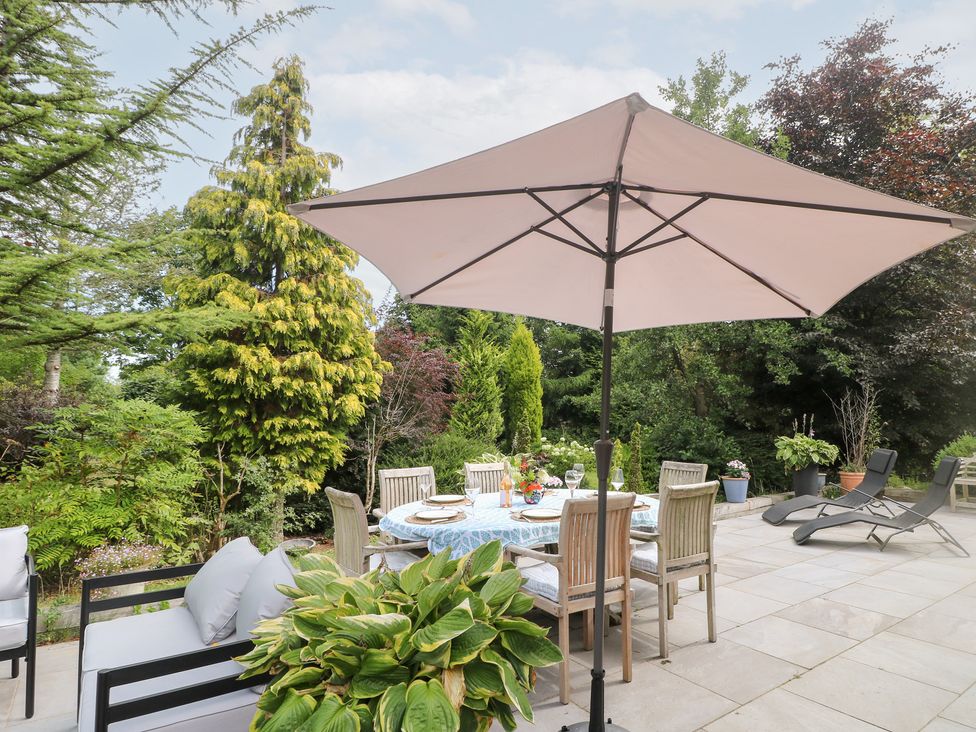 A garden with a dining table and chairs under an umbrella at Ladycroft Barn Ashbourne