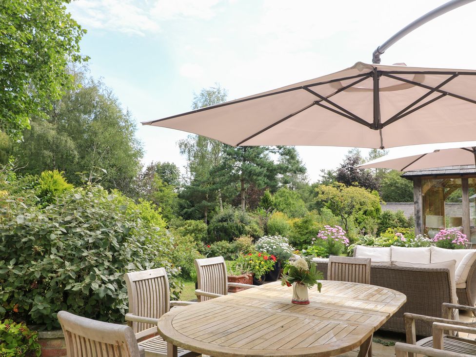 A garden with a table and chairs under an umbrella at Ladycroft Barn Ashbourne