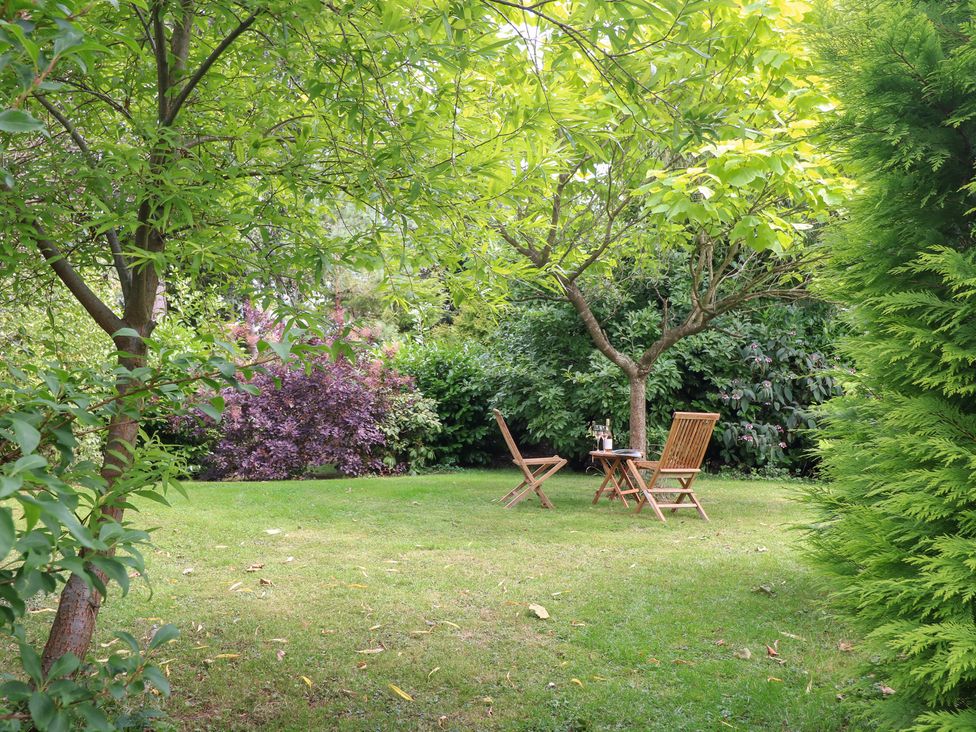 A garden with a table and chairs under a tree at Ladycroft Barn Ashbourne