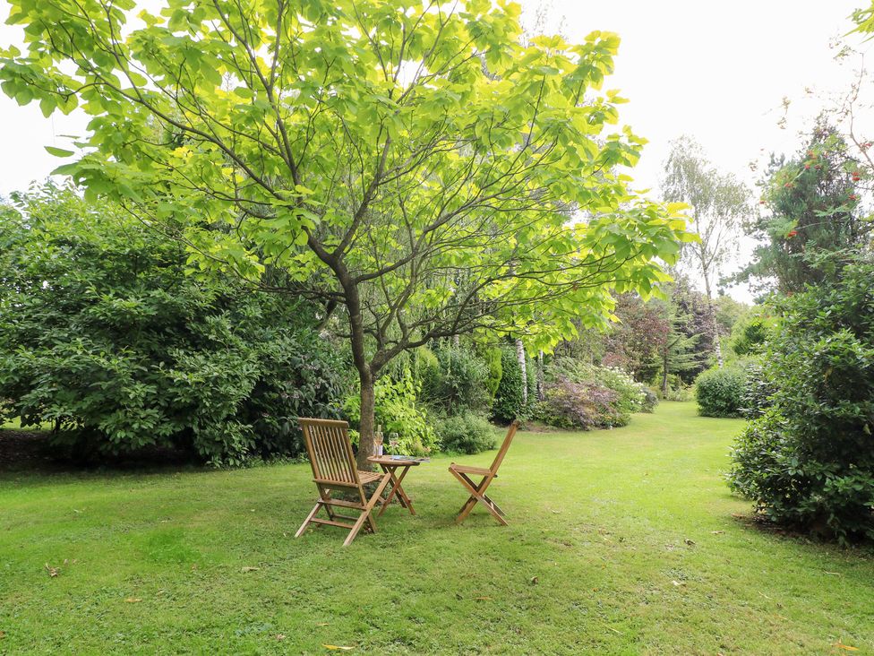 A garden with a table and chairs under a tree at Ladycroft Barn Ashbourne