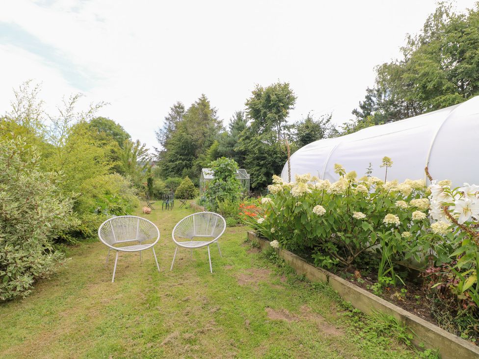 A garden with two chairs and a greenhouse at Ladycroft Barn Ashbourne