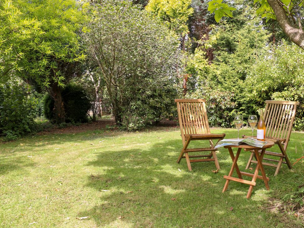 A garden with two chairs and a table holding wine and glasses at Ladycroft Barn Ashbourne