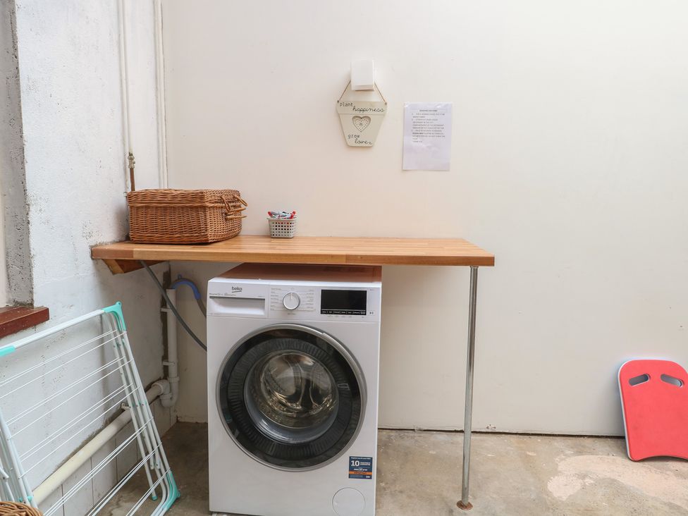 A laundry room with a washing machine and a wooden table at 4 Trafalgar Square Great Yarmouth