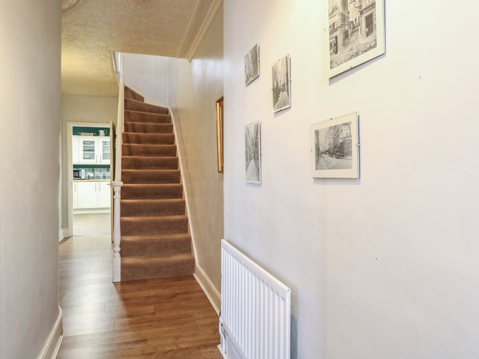 A hallway with a staircase and photographs on the wall at 4 Trafalgar Square Great Yarmouth