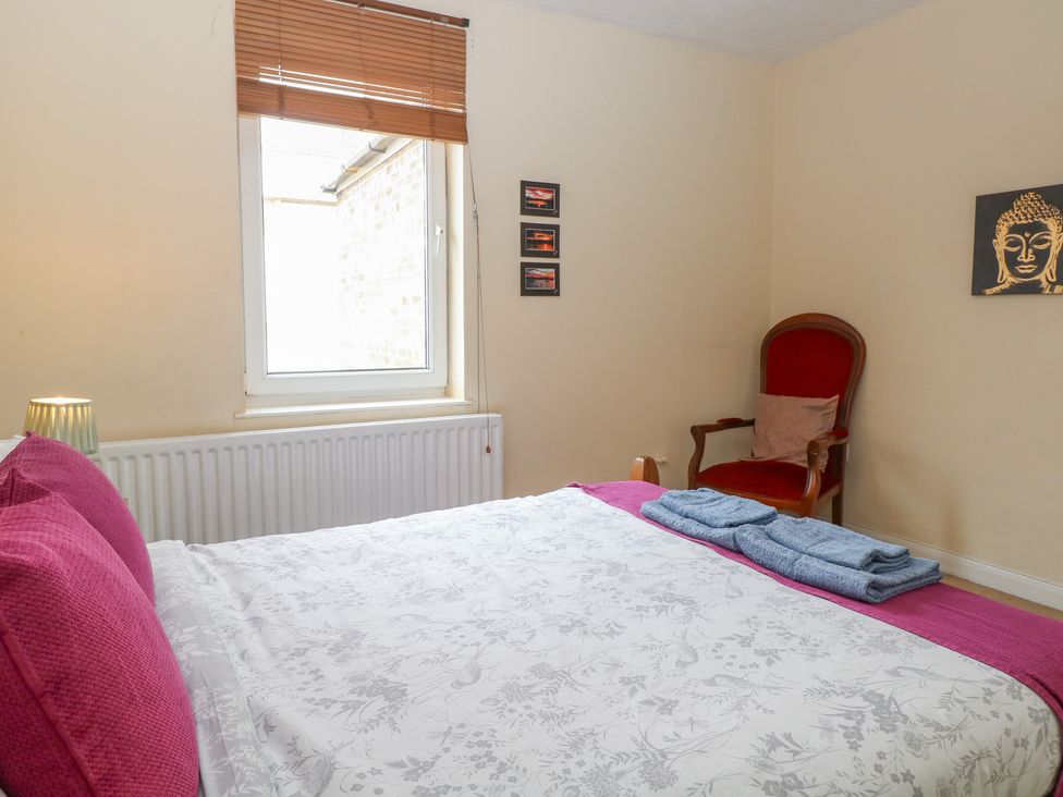 A bedroom with a bed and armchair at 4 Trafalgar Square in Great Yarmouth
