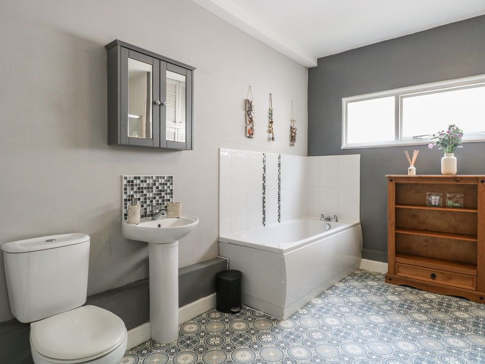 A bathroom with a bathtub, sink, and cabinet at 4 Trafalgar Square in Great Yarmouth