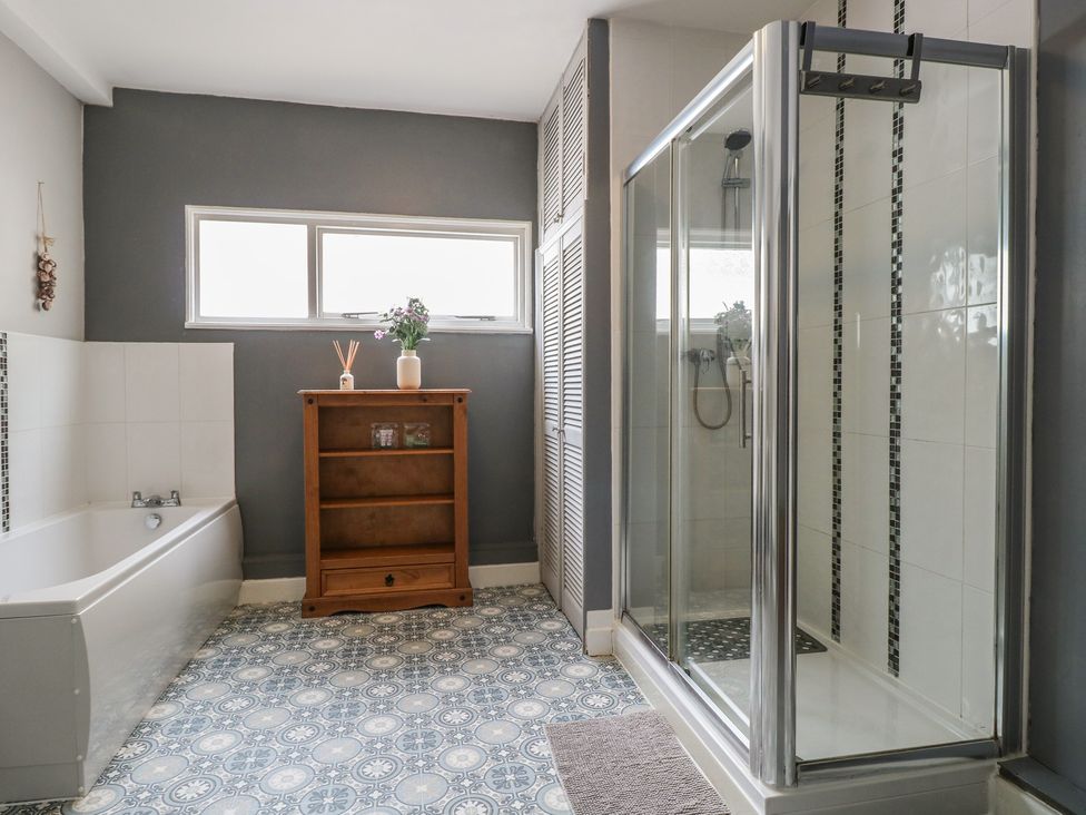 A bathroom featuring a bathtub, shower, and wooden shelf at 4 Trafalgar Square, Great Yarmouth