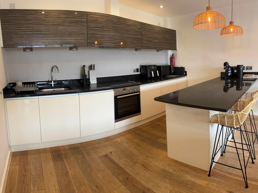 A kitchen with cabinets, countertops, stove and bar stools at Fistral Apres Surf in Newquay