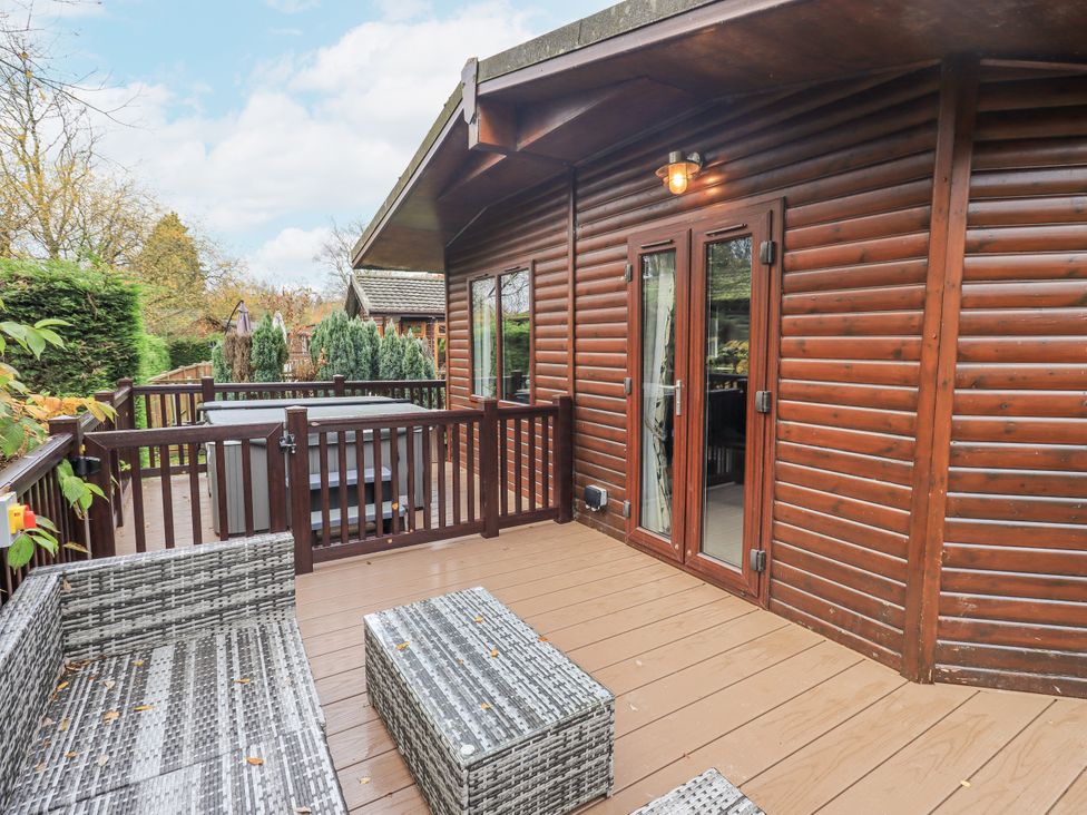 An outdoor patio with seating and a hot tub at Damson Lodge, Thirlmere 8, White Cross Bay, Windermere