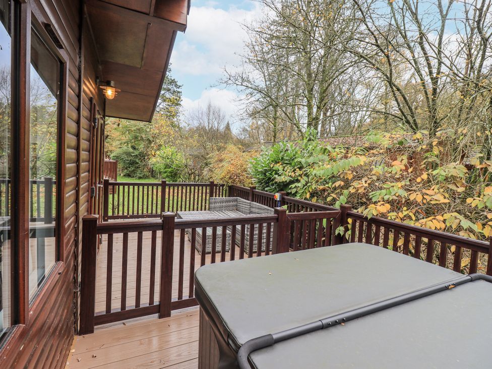 A deck with a hot tub and outdoor furniture at Damson Lodge Thirlmere 8, White Cross Bay, Windermere