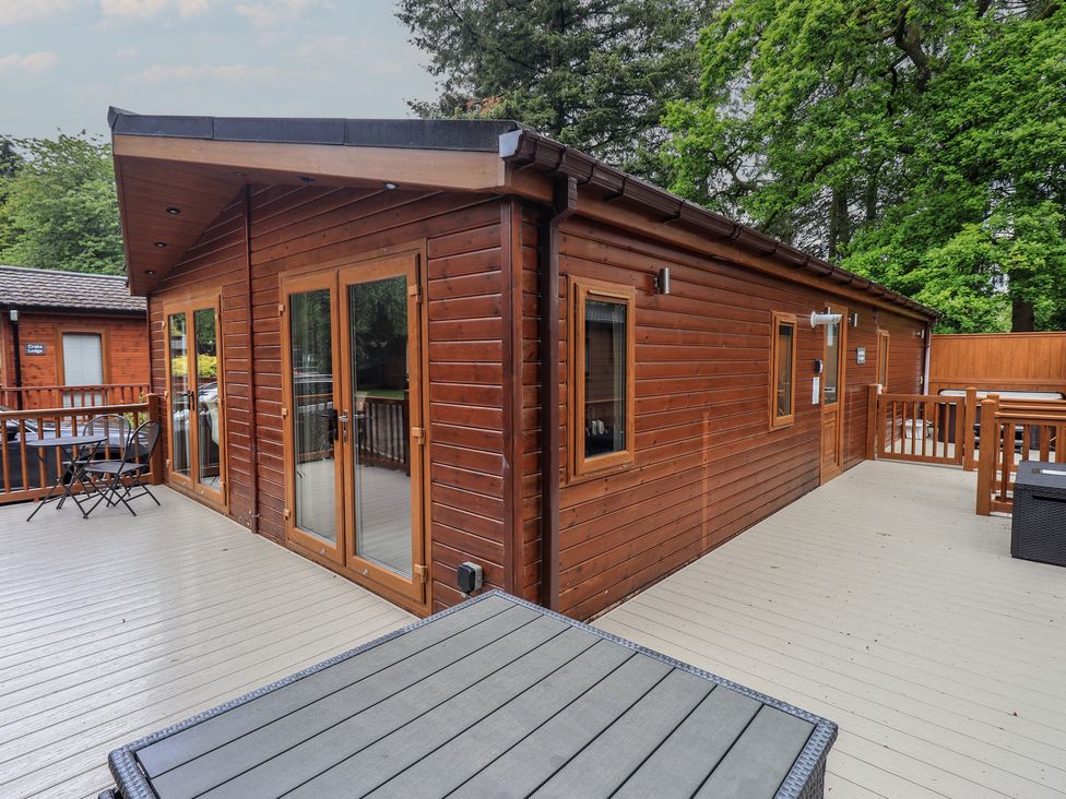 A log cabin with a deck and wooden railing at Ridgway Lodge Calgarth 40, White Cross Bay near Windermere