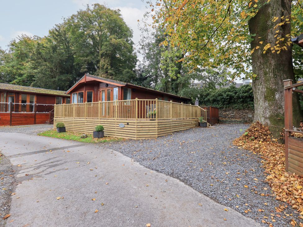 An outdoor area with a lodge and decking at Buttermere Lodge near Glade 5, Fallbarrow Park near Bowness on Windermere