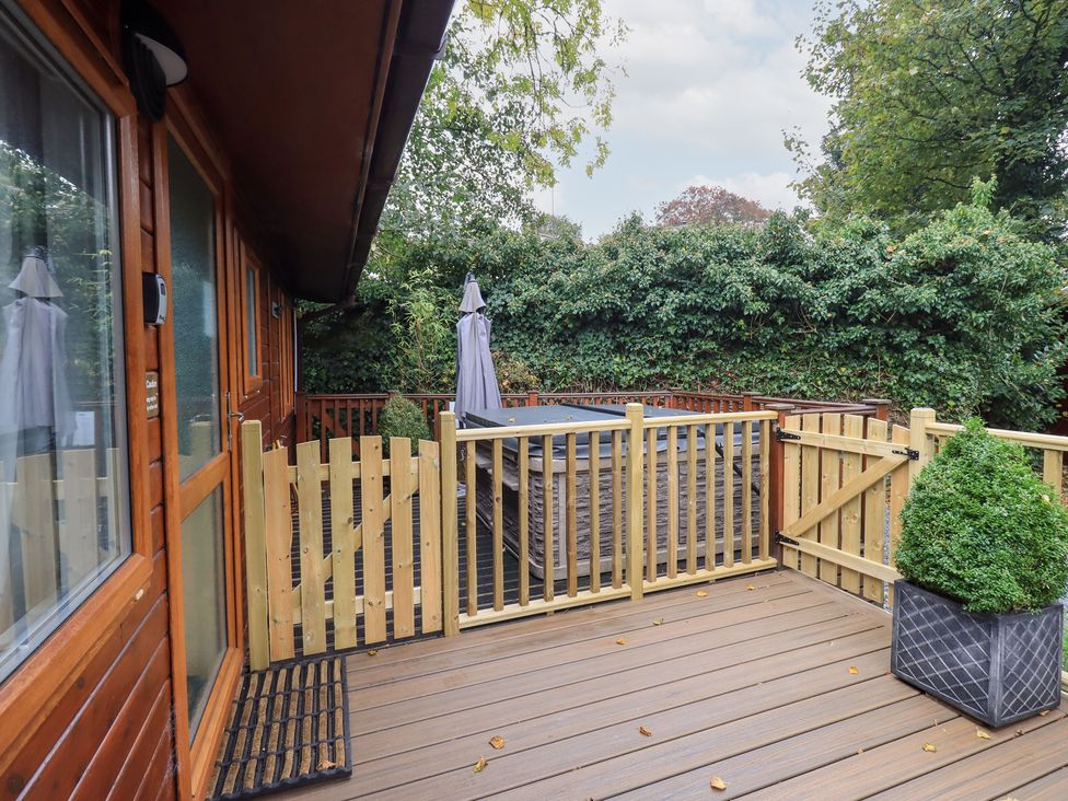 An outdoor area with a hot tub and wooden fence at Buttermere Lodge Glade 5, Fallbarrow Park near Bowness on Windermere