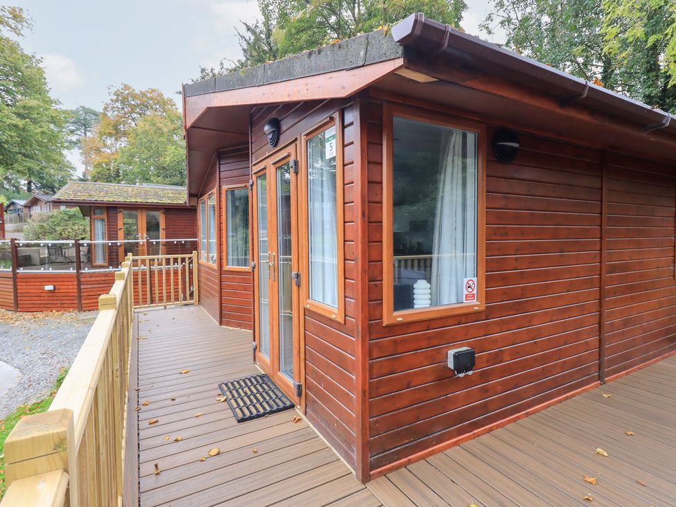 An outdoor area with a cabin and decking at Buttermere Lodge, Glade 5, Fallbarrow Park near Bowness on Windermere