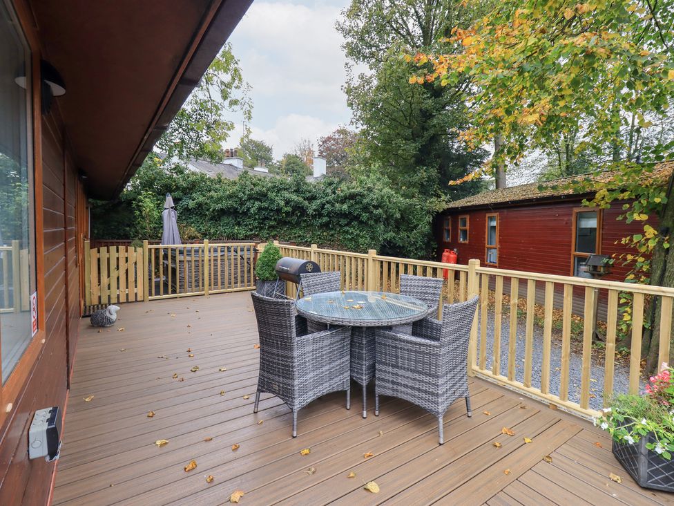 A deck with a table and chairs at Buttermere Lodge, Glade 5, Fallbarrow Park near Bowness on Windermere