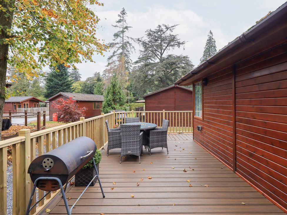 A patio with a table and chairs at Buttermere Lodge, Glade 5, Fallbarrow Park near Bowness on Windermere