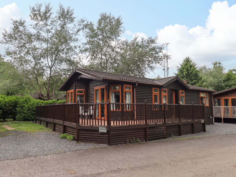 A lodge with a deck surrounded by trees at Rydal Lodge in Grasmere 24, White Cross Bay near Windermere