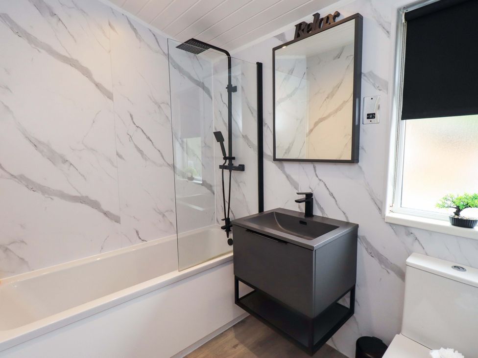 A bathroom featuring a bathtub, shower, mirror, sink, and toilet at Rydal Lodge Grasmere 24, White Cross Bay near Windermere