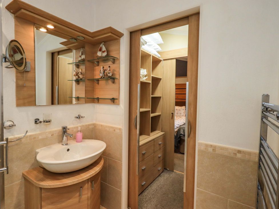 A bathroom featuring a sink, mirror, and storage unit at Elder Lodge Kirkstone 5, Limefitt Park near Windermere
