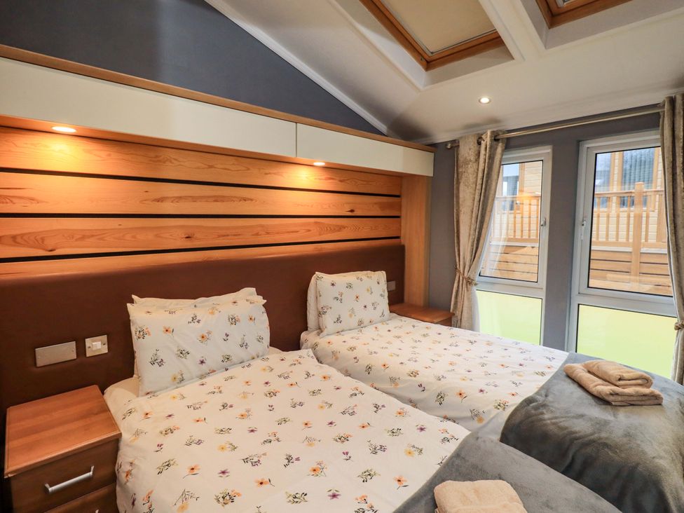 A bedroom with two beds and windows at Elder Lodge, Kirkstone 5, Limefitt Park near Windermere