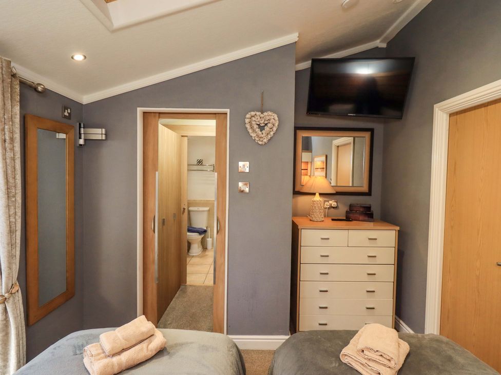 A bedroom with a bed and dresser at Elder Lodge Kirkstone 5, Limefitt Park near Windermere