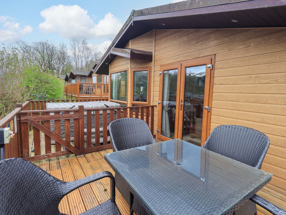 An outdoor seating area with a hot tub and table at Elder Lodge in Kirkstone 5, Limefitt Park near Windermere
