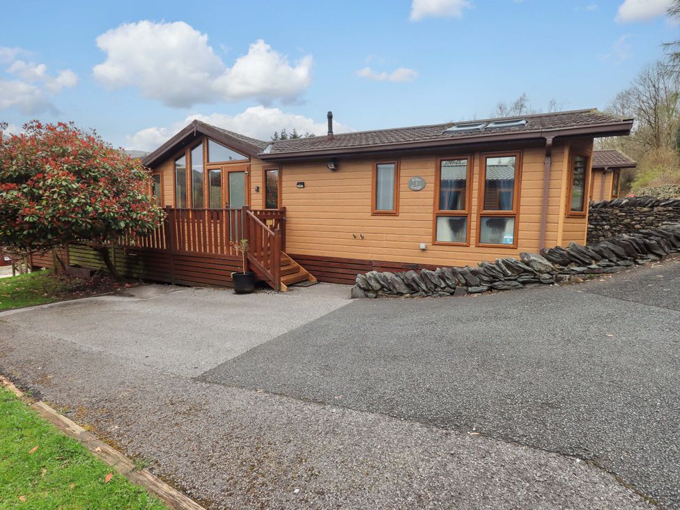 A wooden cabin with a deck and parking area at Elder Lodge Kirkstone 5 Limefitt Park near Windermere