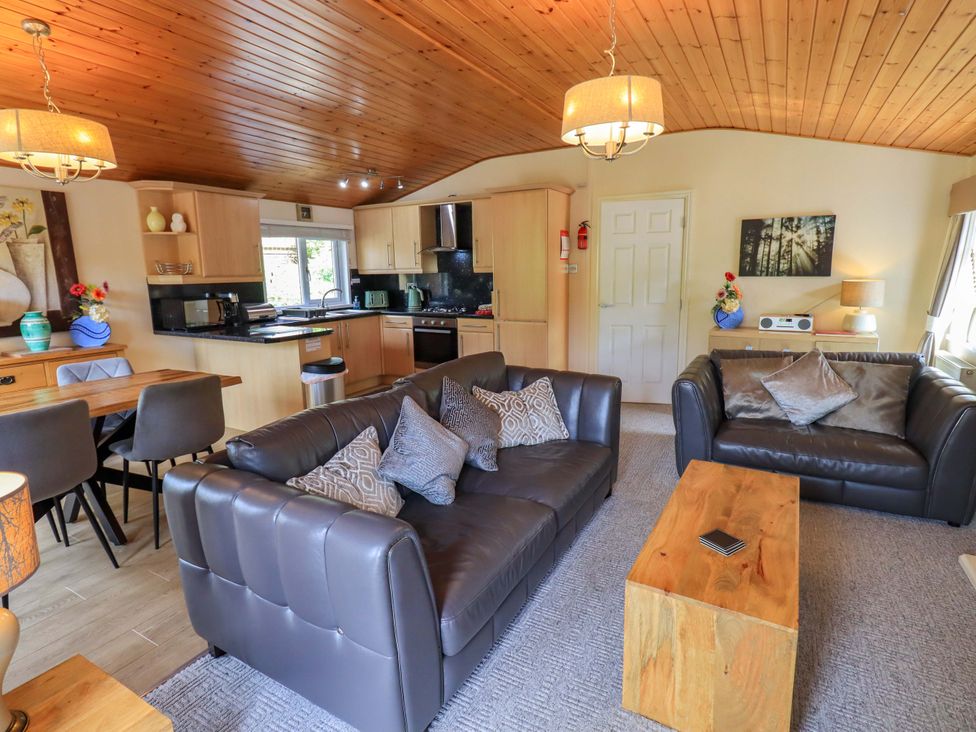 A living room with a sofa, coffee table, and dining area at Birthwaite Lodge, Fellside 6, Limefitt Park near Windermere