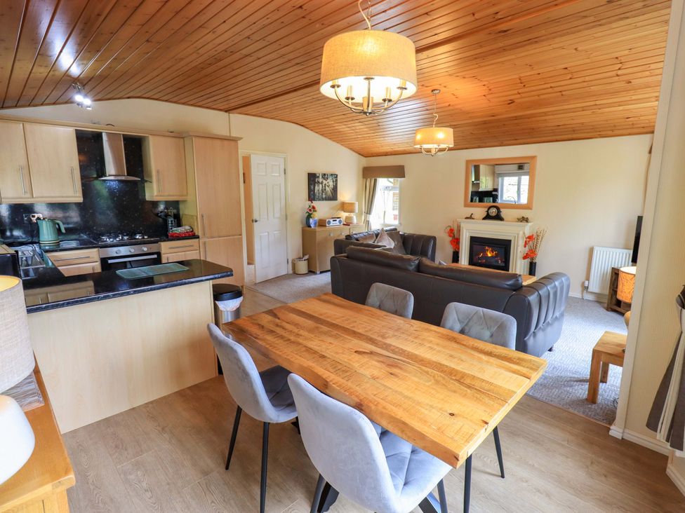 A living room with a kitchen area and dining table at Birthwaite Lodge, Fellside 6, Limefitt Park near Windermere