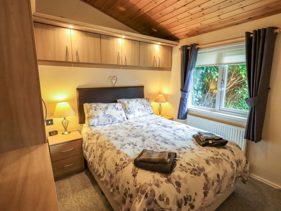 A bedroom with a bed and lamp at Birthwaite Lodge Fellside 6, Limefitt Park near Windermere