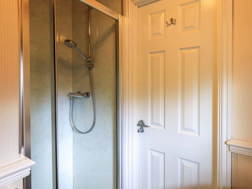 A shower with a white door in a bathroom at Birthwaite Lodge, Fellside 6, Limefitt Park near Windermere