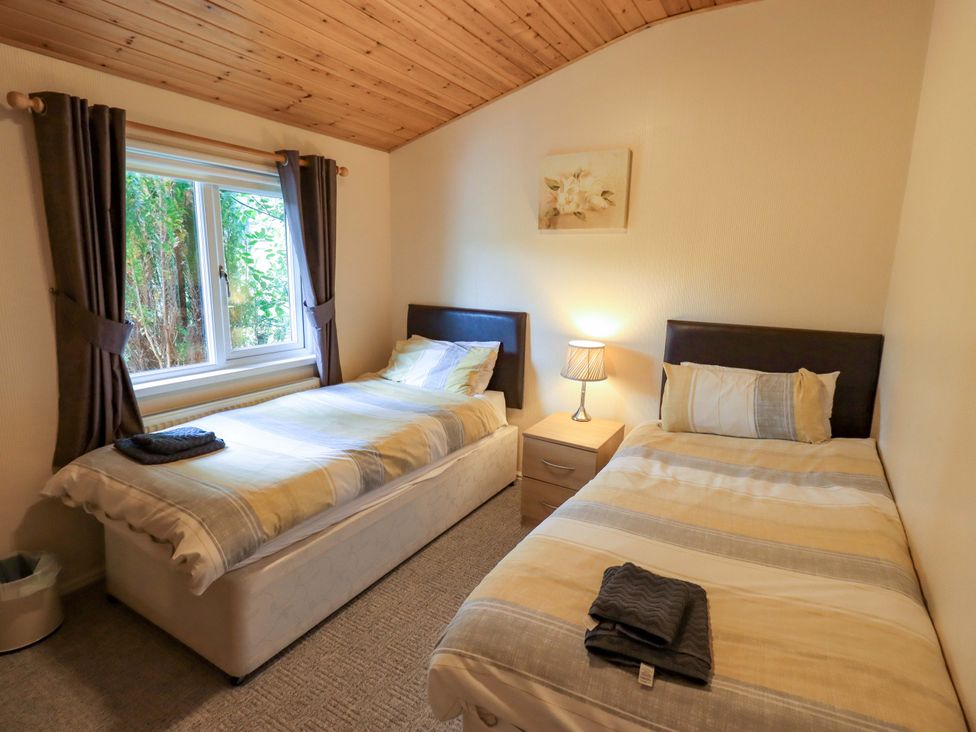 A bedroom with two beds and a window at Birthwaite Lodge, Fellside 6, Limefitt Park near Windermere