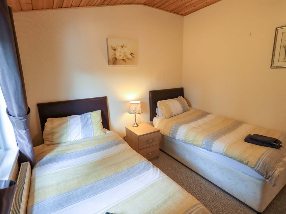 A bedroom with two single beds and a bedside table at Birthwaite Lodge, Fellside 6, Limefitt Park near Windermere